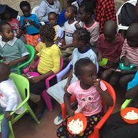 A group of children sitting in chairs eating food.