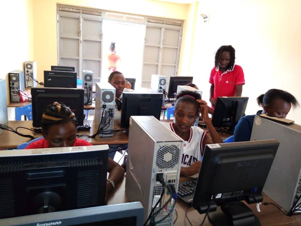 A group of children sitting at computers in front of windows.