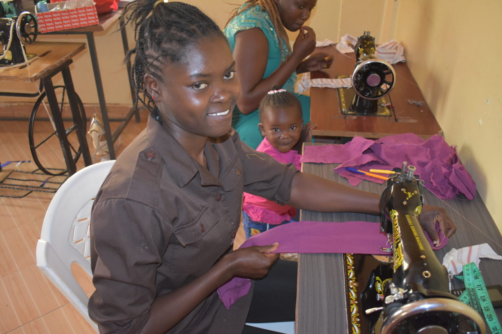 A woman smiles while sewing with her child.