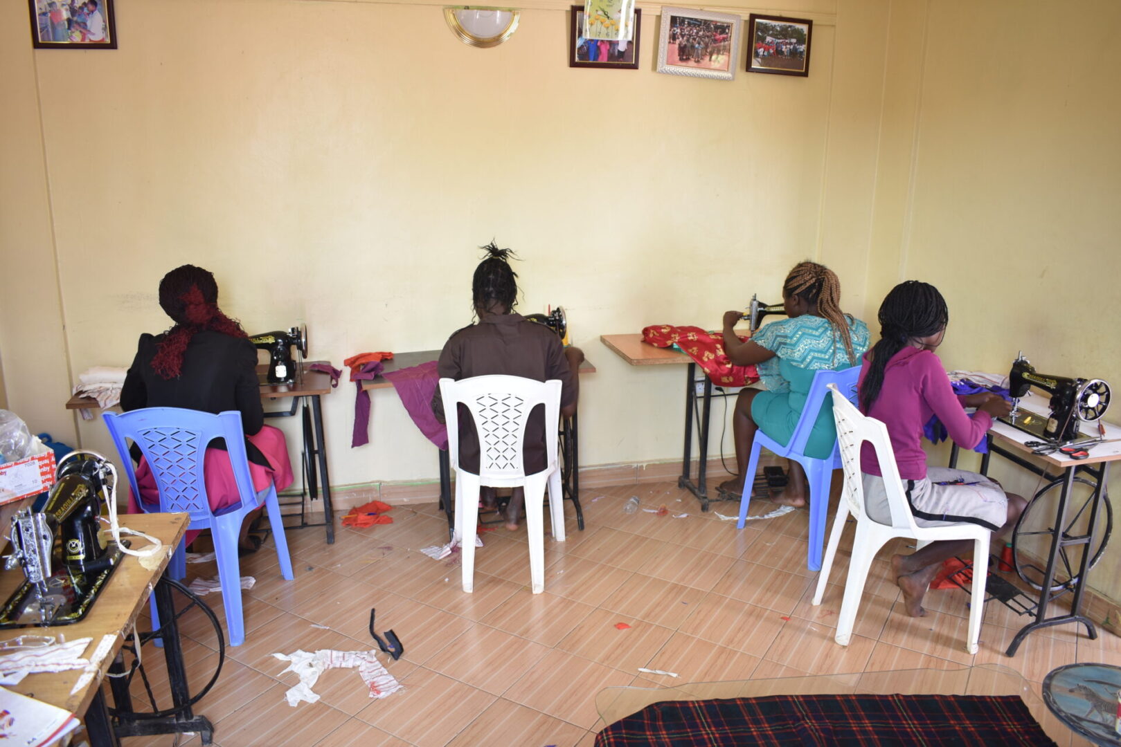 A group of people sitting around tables sewing.