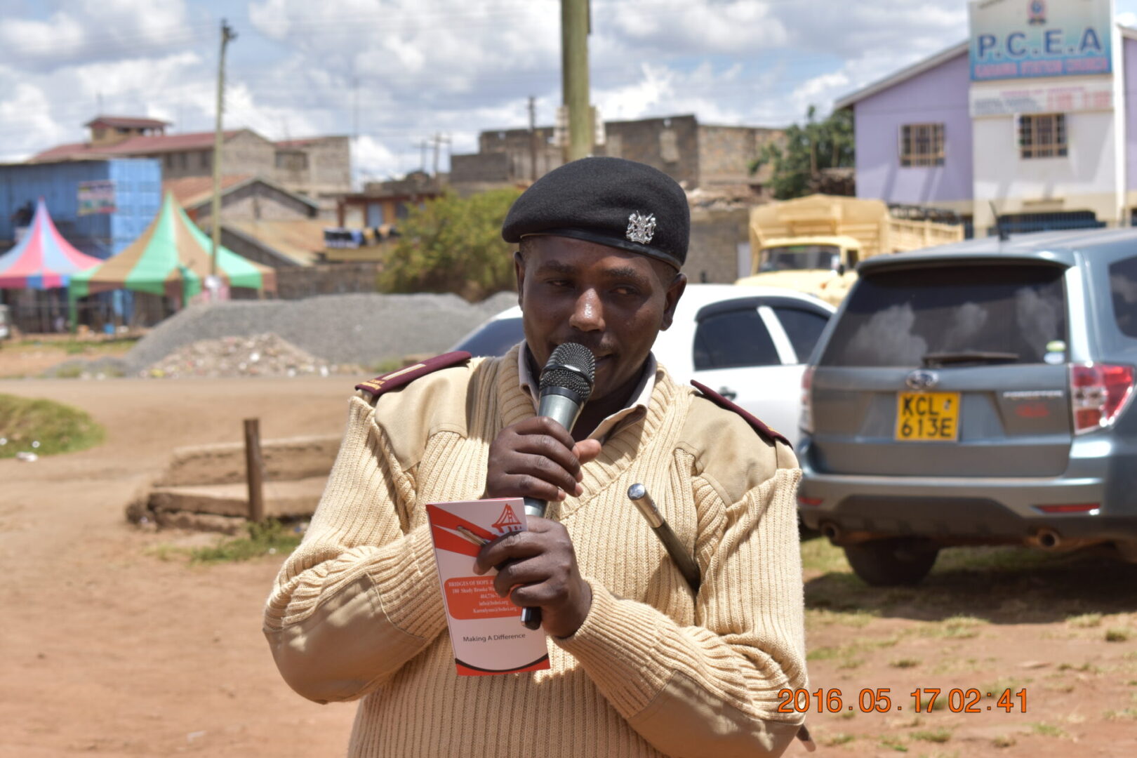 A man holding onto a cup while standing on the side of the road.