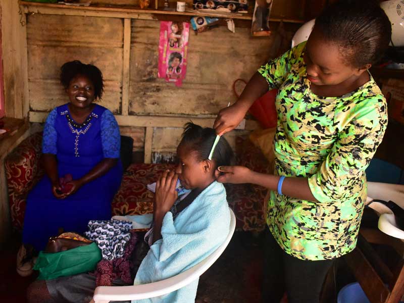 A woman is cutting the hair of a child.