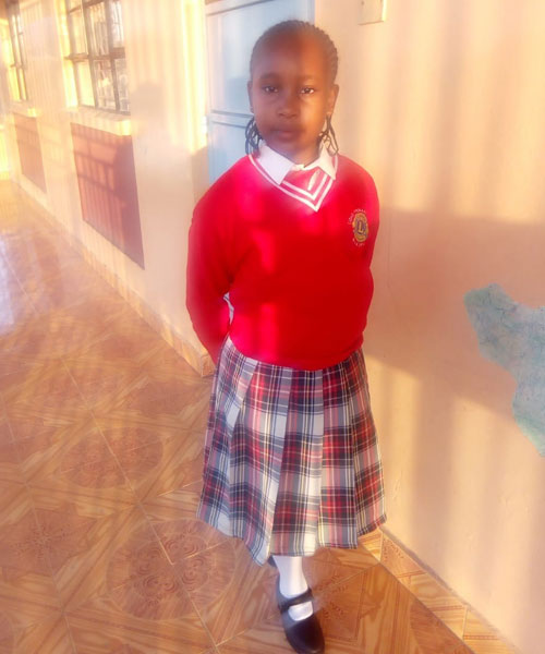 A young girl in school uniform standing on the floor.
