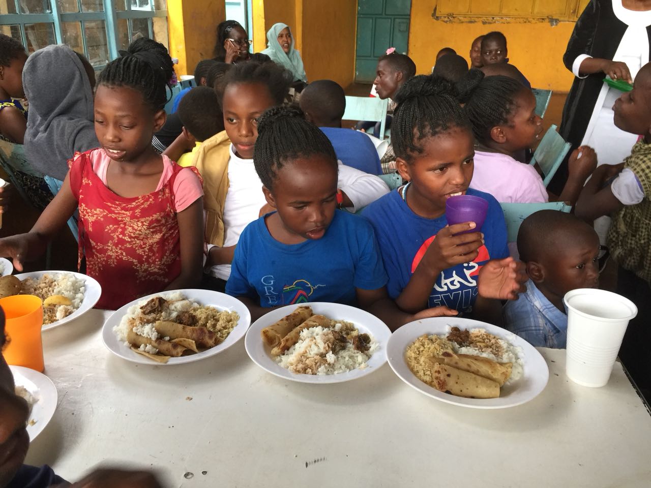 A group of children sitting at a table eating food.