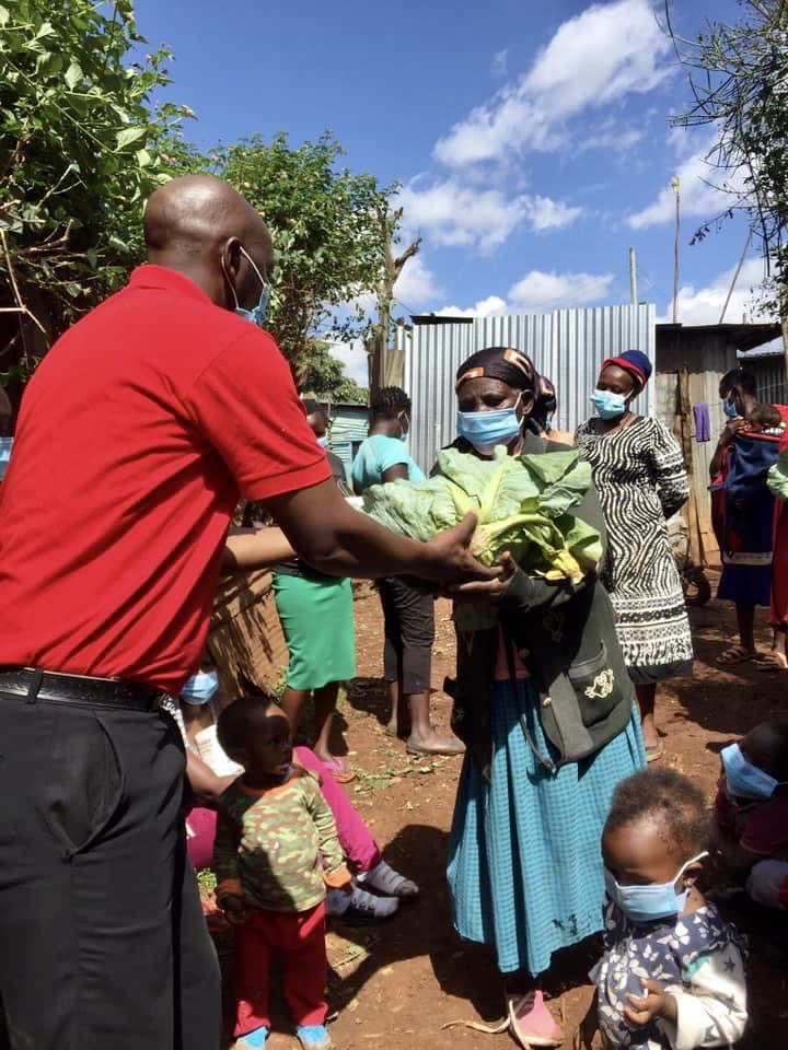 A man in red shirt handing bananas to woman.