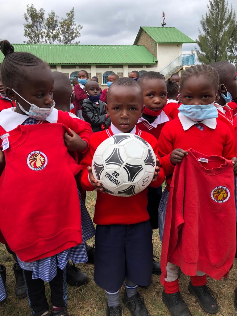 A group of children in red shirts holding a soccer ball.
