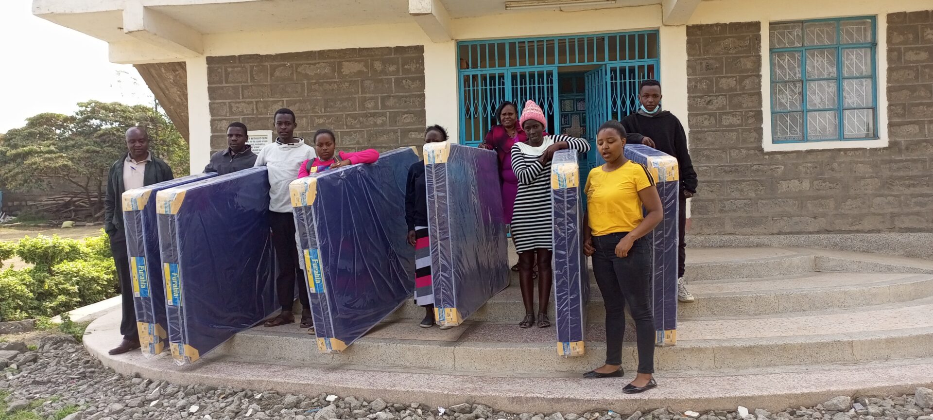 A group of people standing next to some mattresses.