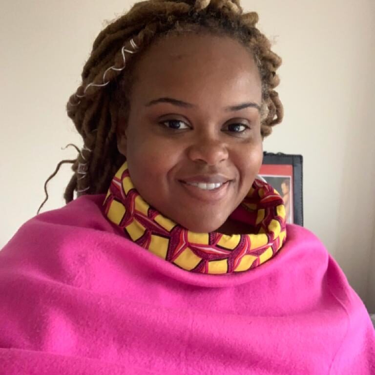 A woman with dreadlocks wearing a pink blanket.